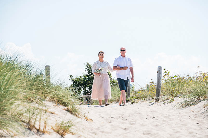 Braut und Brautvater laufen zur Trauung am Strand an der Ostsee