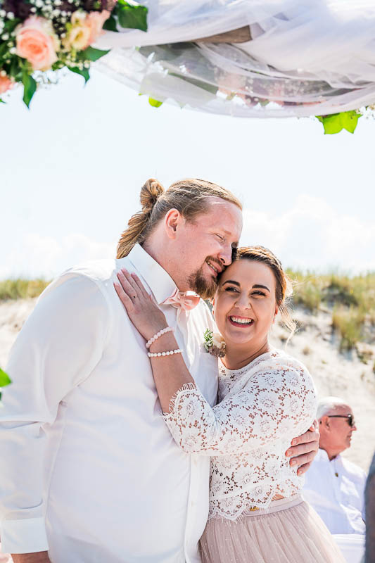 Glückliches Brautpaar nach dem Ja-Wort zur Strandhochzeit in Ahrenshoop beim "Künstlerquartier Seezeichen". Hochzeitsfotograf für authentische Hochzeitsfotos