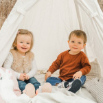Zweijährige Zwillinge sitzen im Tipi-Zelt.