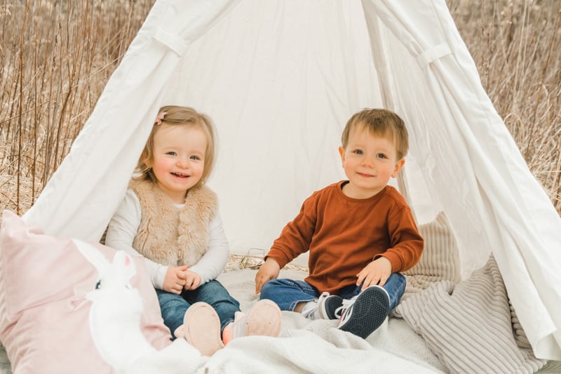 Zweijährige Zwillinge sitzen im Tipi-Zelt.