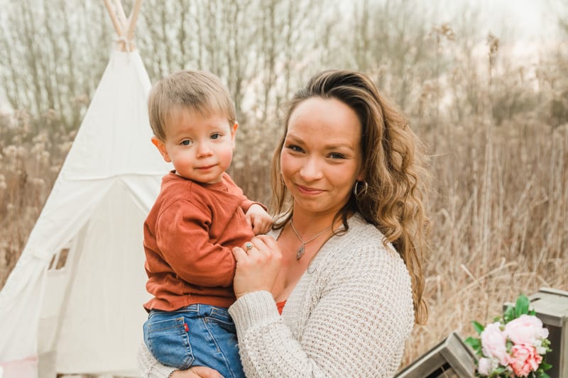 Mama mit ihrem zweijährigen Sohn im Feld vor einem Tipi-Zelt.