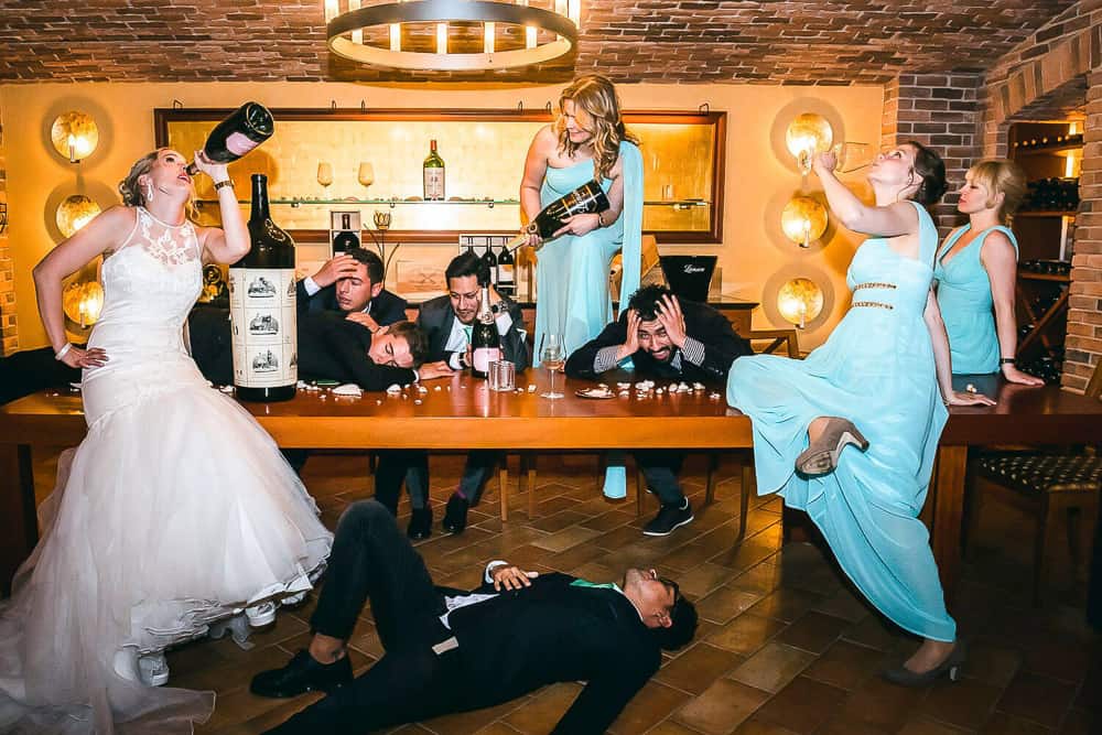 Lustiges Gruppenfoto mit Alkoholflaschen im Weinkeller.