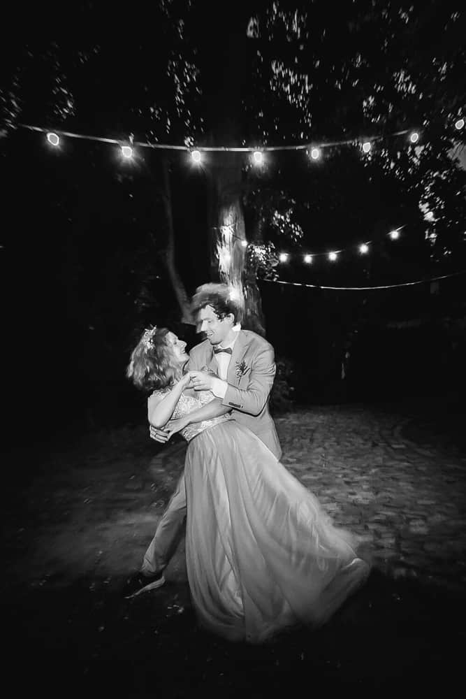Schwarzweißfoto in der Nacht: Brautpaar tanzt im Dunklen mit Lichterketten. Hochzeitsfotograf Lalendorf