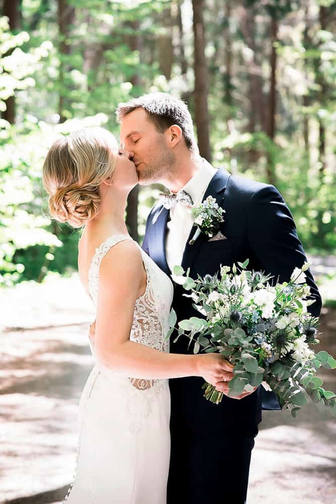 Brautpaarshooting im Wald und Sonnenschein mit modernem Brautstrauß. Hochzeitsfotograf Ahrenshoop.