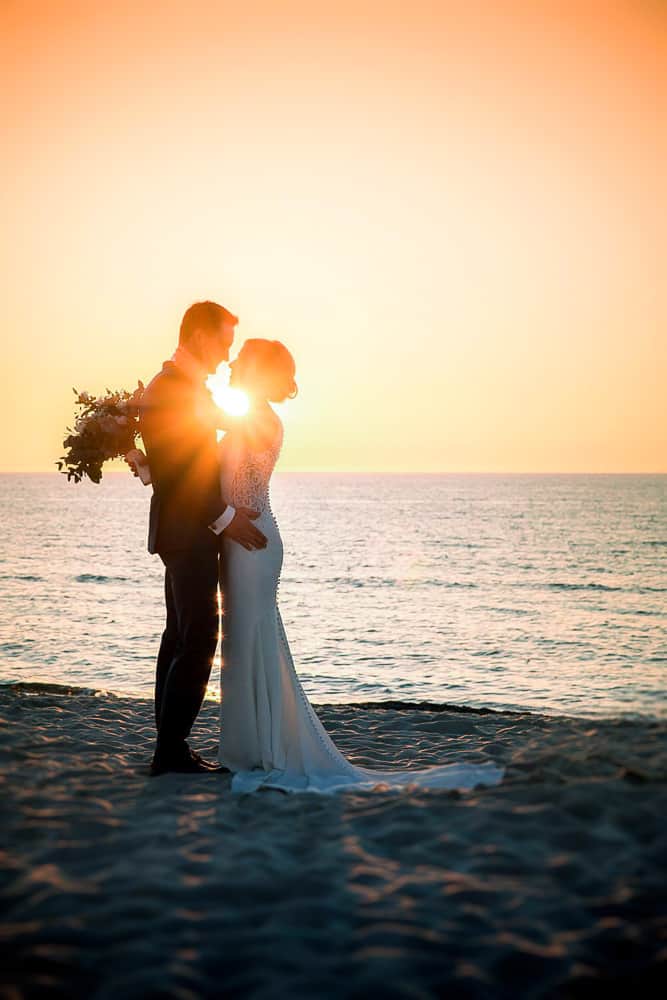 Hochzeitsfoto zum Sonnenuntergang am Strand von Dierhagen. Das Brautpaar schaut sich tief in die Augen und die untergehende Sonne scheint durch sie hindurch. Hochzeitsfotograf Ahrenshoop.