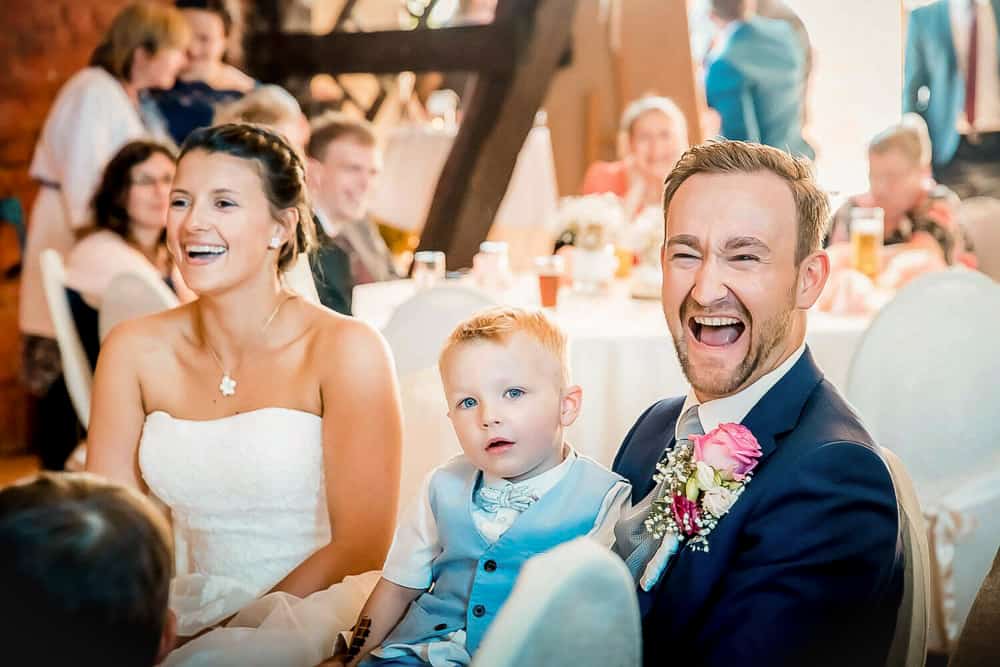 Bräutigam, Braut und Sohn lachen während der Rede des Brautvaters.