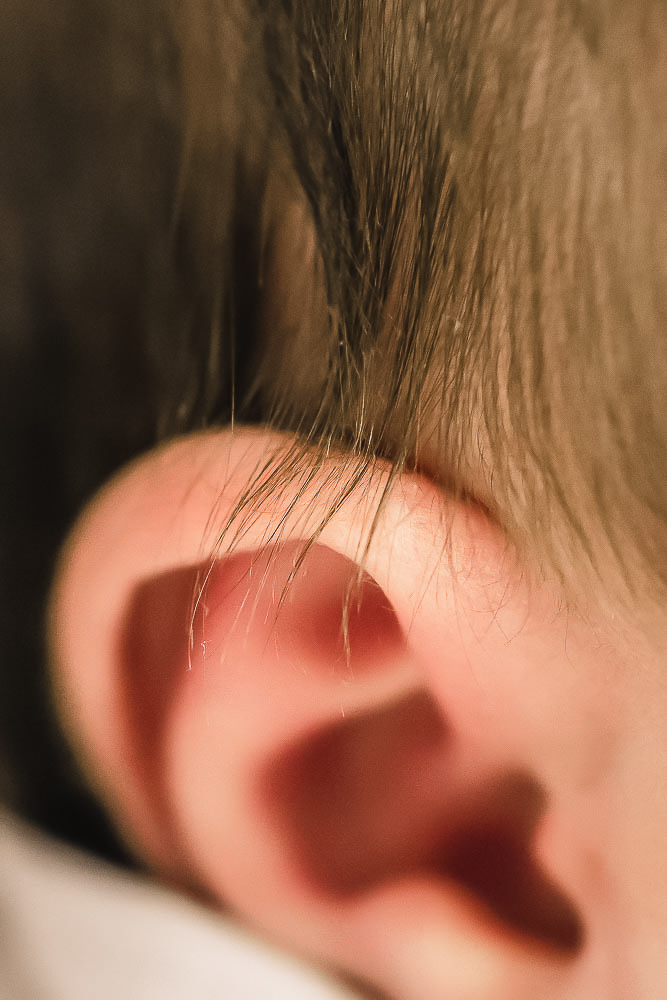 Dunkle Haare über Ohr vom neugeborenen Baby