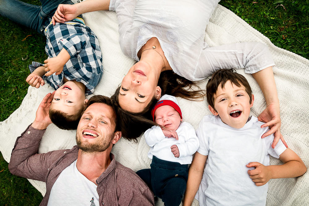 Familienbild von oben: Eltern und ihre drei Söhne inklusive neugeborenen Baby