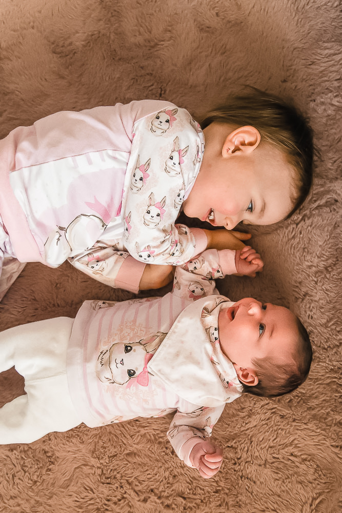 Große Schwester bestaunt ihr neugeborenes Geschwister-Baby
