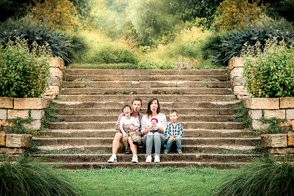 Familie mit drei Söhnen sitzt auf einer Treppe im Botanischen Garten Rostock