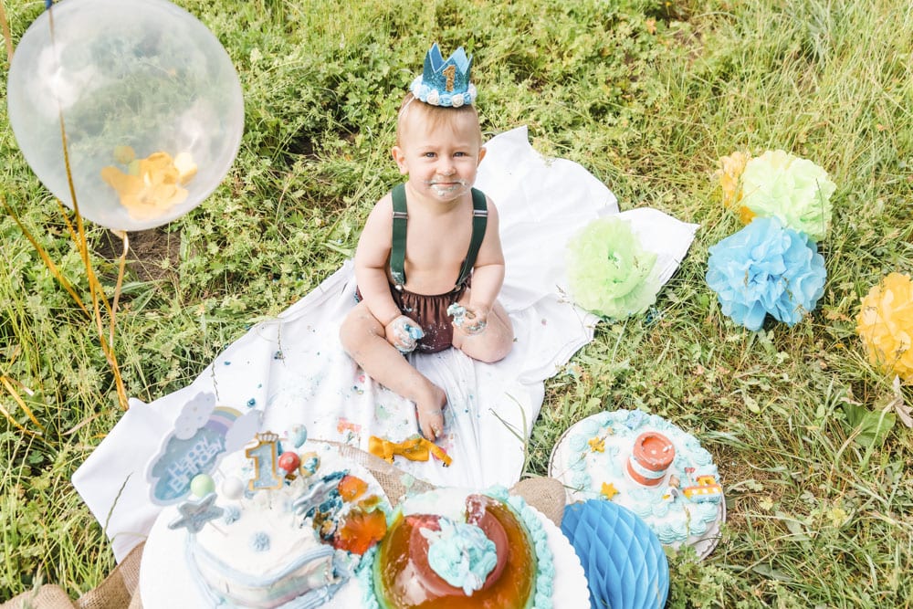 Einjähriger verputzt mehrere Geburtstagskuchen auf einer Wiese