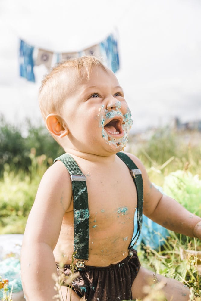 Einjähriger hat ein mit Kuchen verschmutztes Gesicht und freut sich