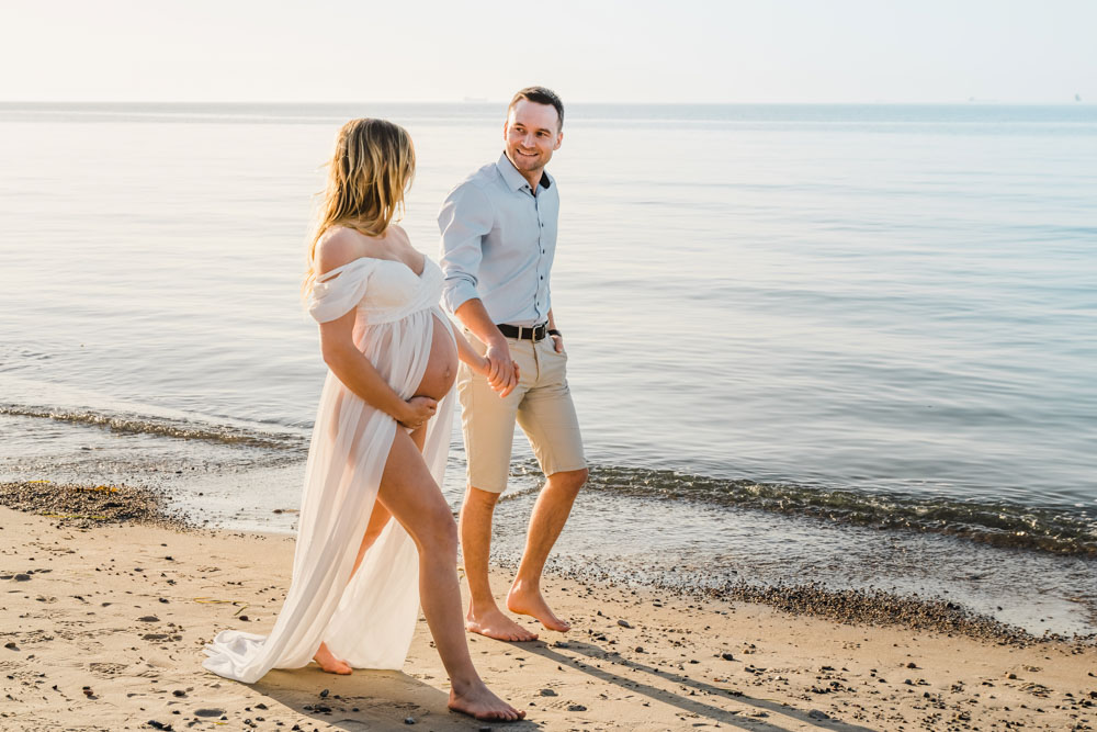 Spaziergang von schwangerer Frau und dem werdenden Papa am Strand