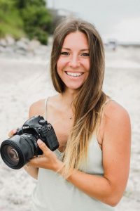 Fotografin hält ihre Kamera am Strand in der Hand