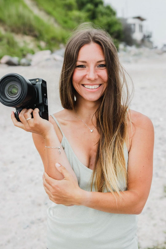 Fotografin steht am Strand mit ihrer Kamera