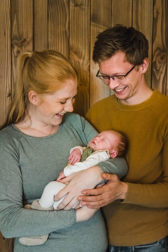 Die frischgebackenen Eltern halten ihr neugeborenes Baby im Arm und sind voller Stolz.