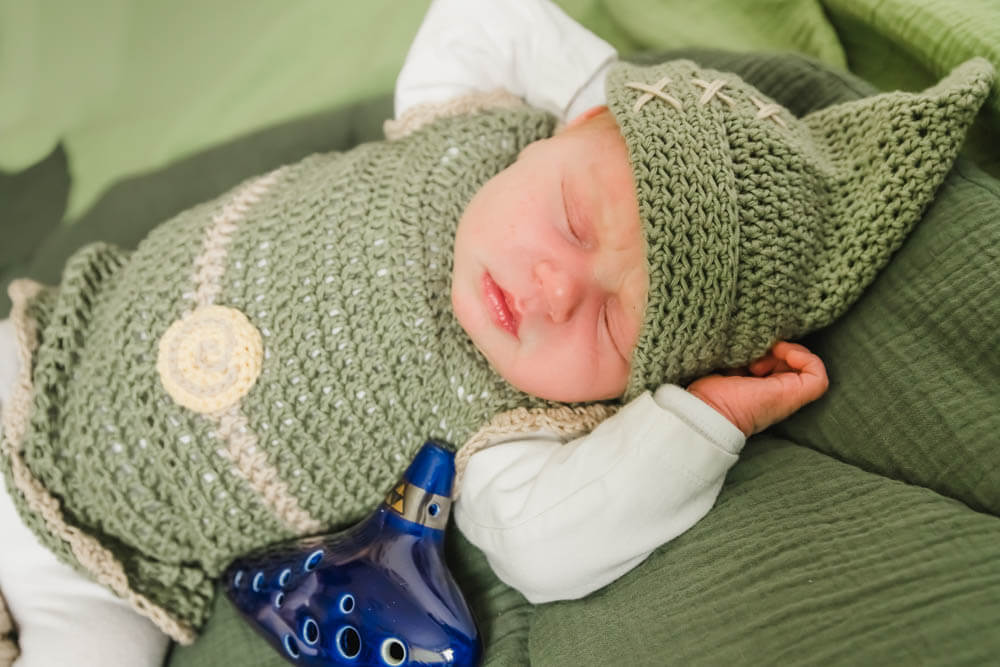 Neugeborenes Baby schläft und ist als Zelda verkleidet.