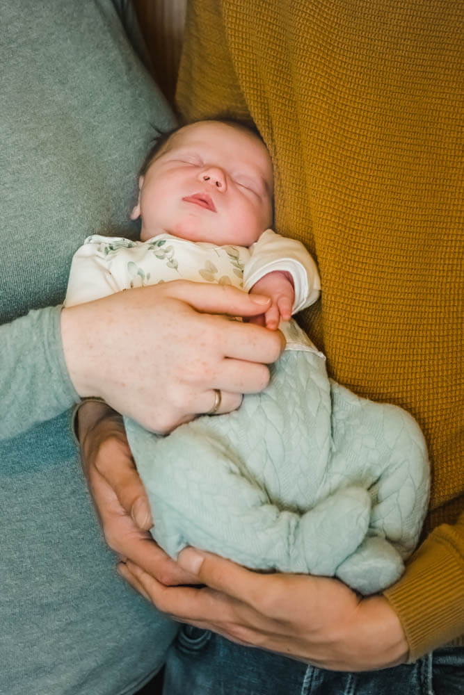 Neugeborenes Baby kuschelt und schläft zwischen Mama und Papa.