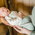 Neugeborenes Baby wird zwischen frischgebackenen Eltern gehalten. Babyfotograf Rostock.