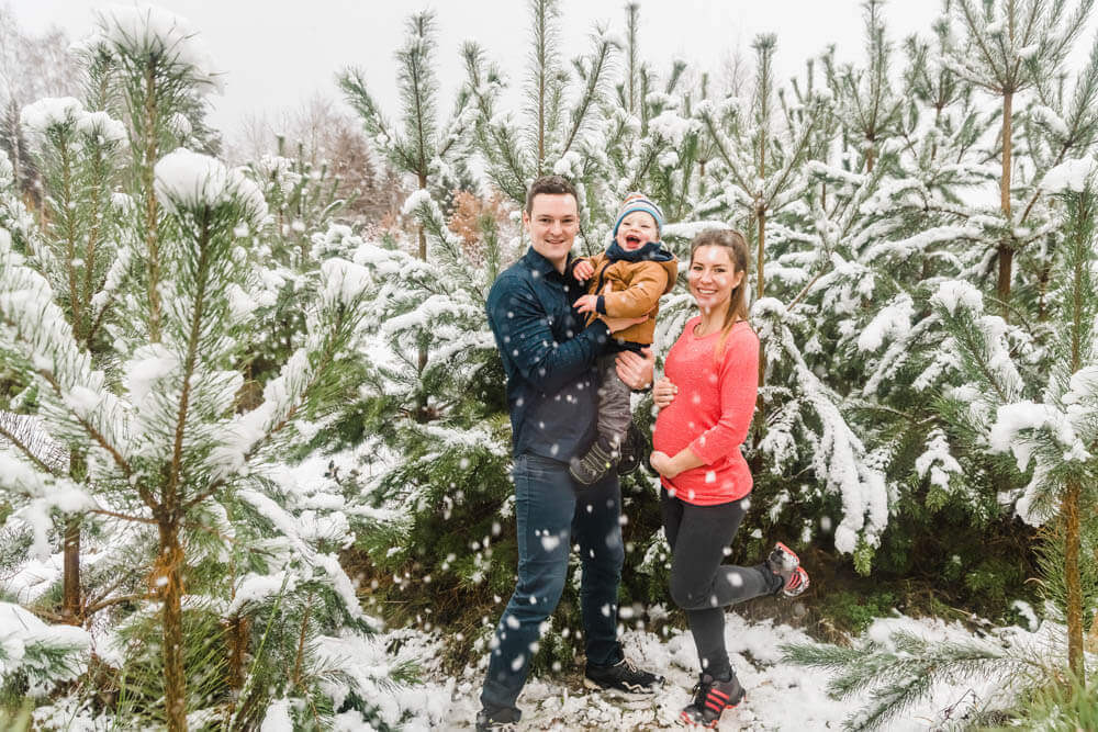 Große Freude beim Familien-Fotoshooting im Schnee zwischen Tannenbäumen.