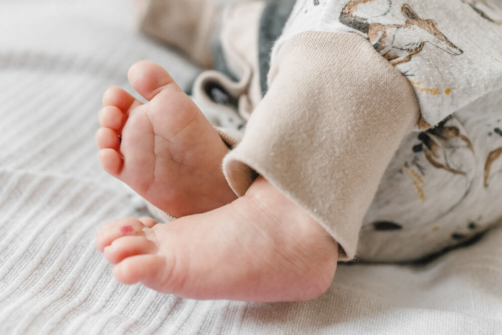 Detailaufnahme der Füße vom neugeborenen Baby beim Fotoshooting Zuhause