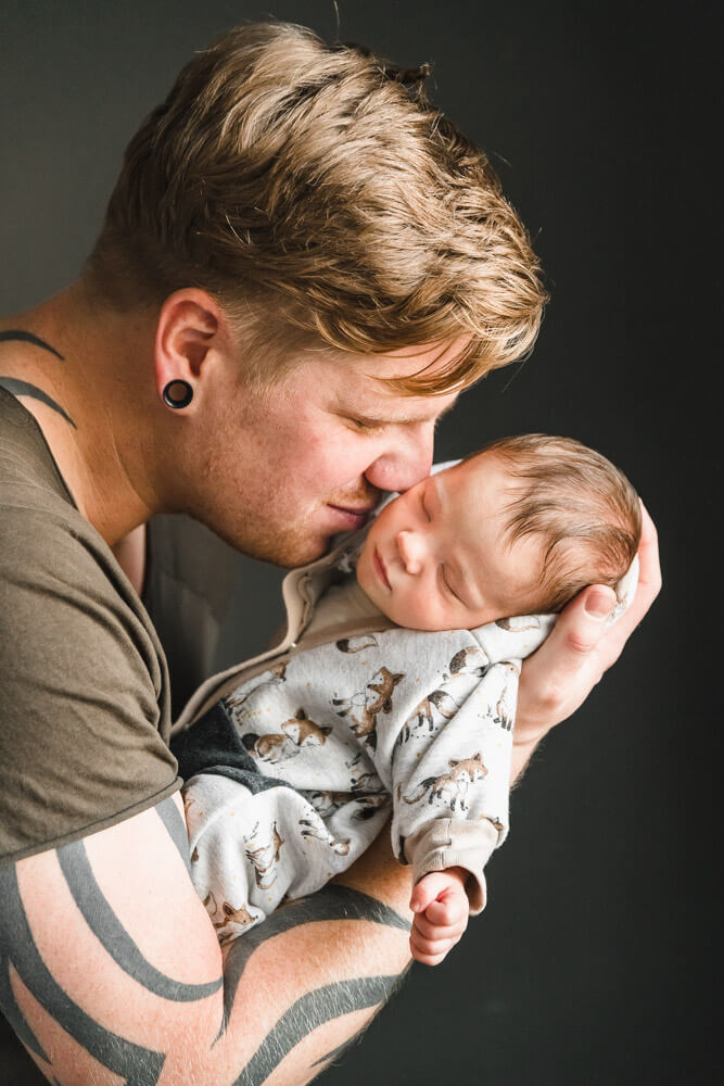 Papa kuschelt sein neugeborenes Baby beim Fotoshooting Zuhause