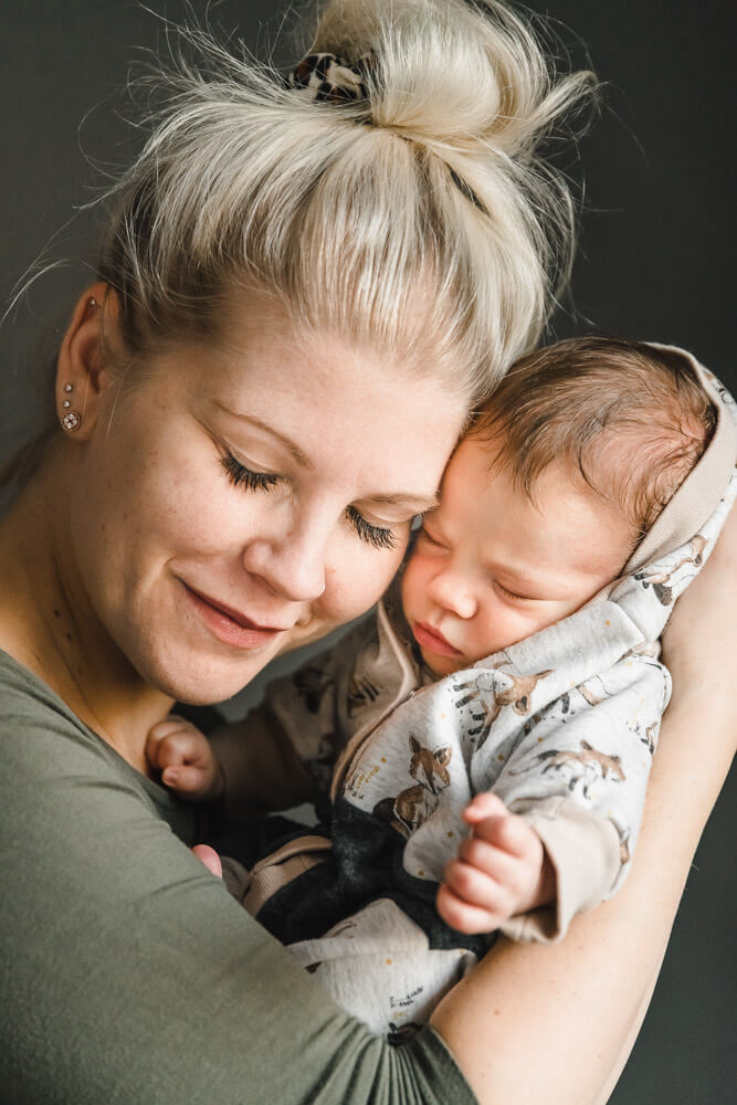 Mama kuschelt ihr neugeborenes Baby beim Fotoshooting Zuhause
