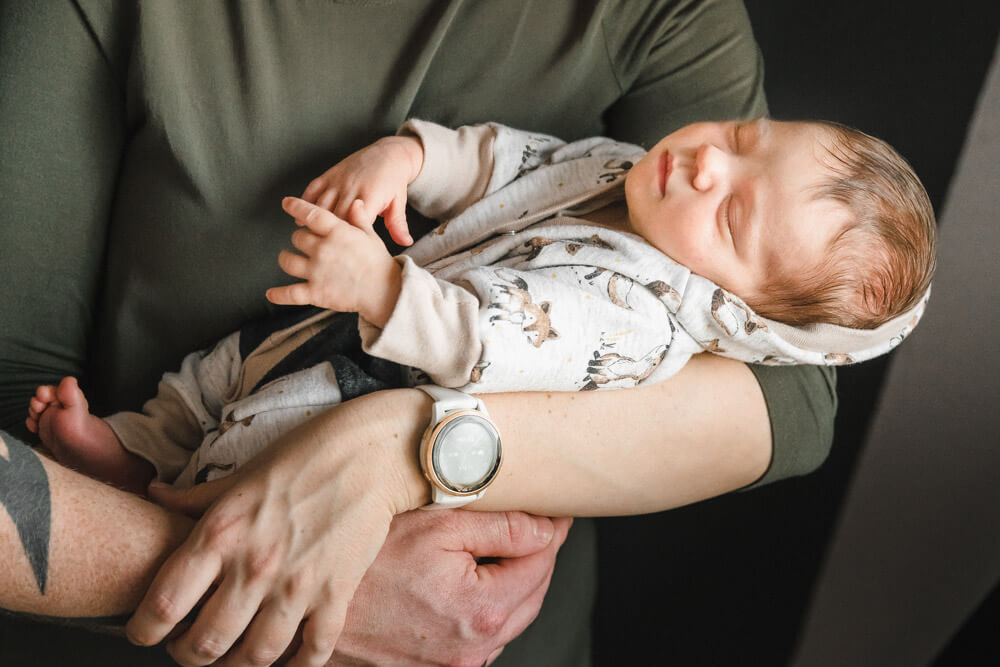 Baby schläft im Arm vom Papa beim Babyfotoshooting