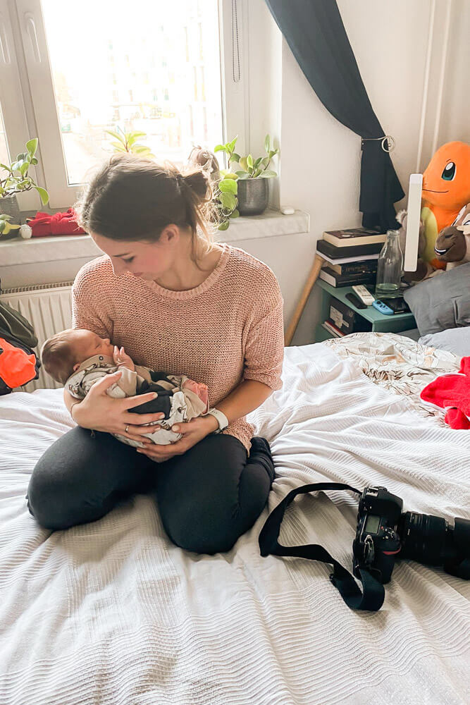 Fotografin kuschelt neugeborenes Baby während dem Homestory-Fotoshooting