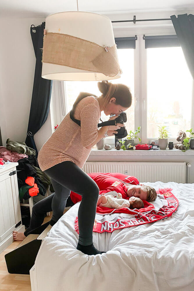 Fotograf fotografiert Baby und Papa beim Fotoshooting Zuhause