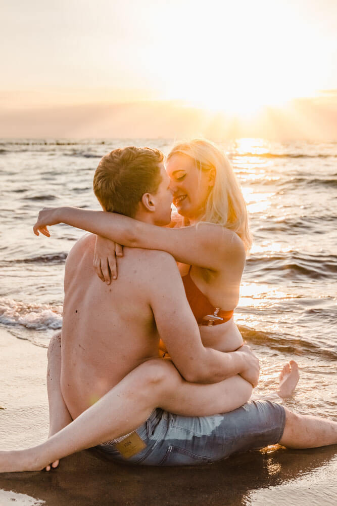 Paar küsst sich fast beim Sonnenuntergang am Strand