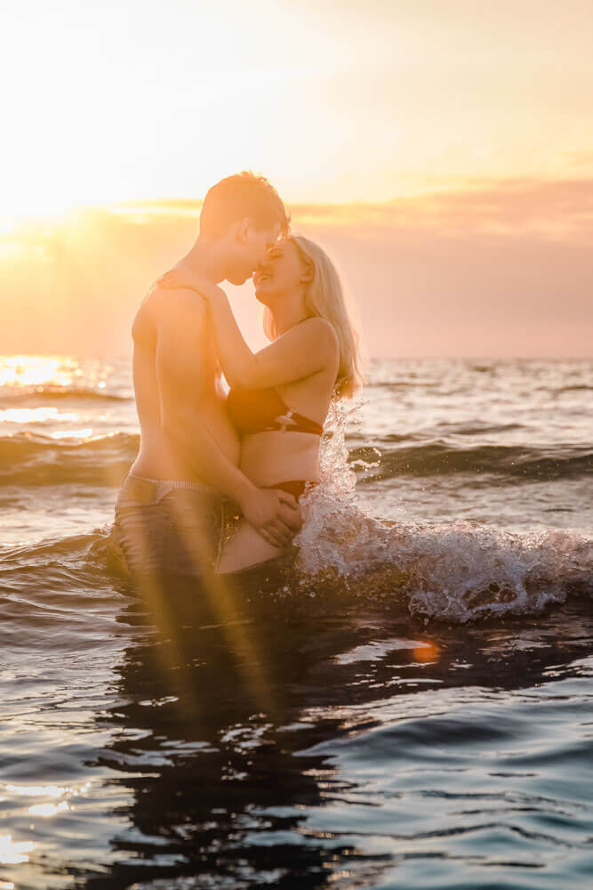 Pärchen im Wasser ist kurz vorm Küssen am Strand von Warnemünde zum Sonnenuntergang