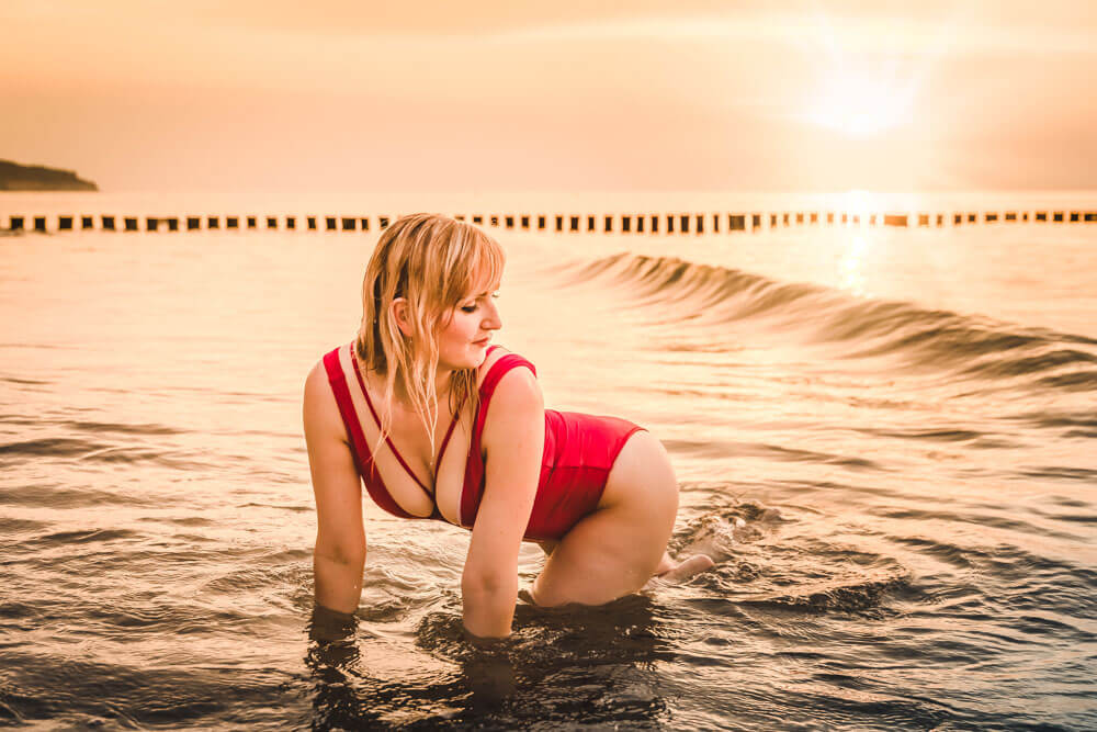 Junge Frau posiert während des Sonnenunterganges im Wasser der Ostsee