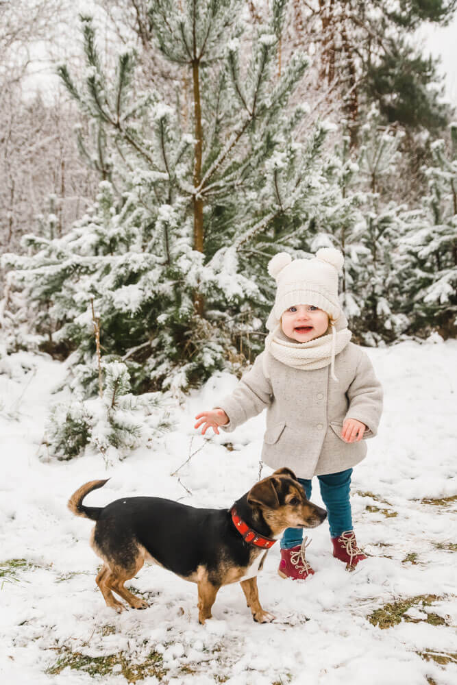 Kleinkind im Schnee mit Hündin