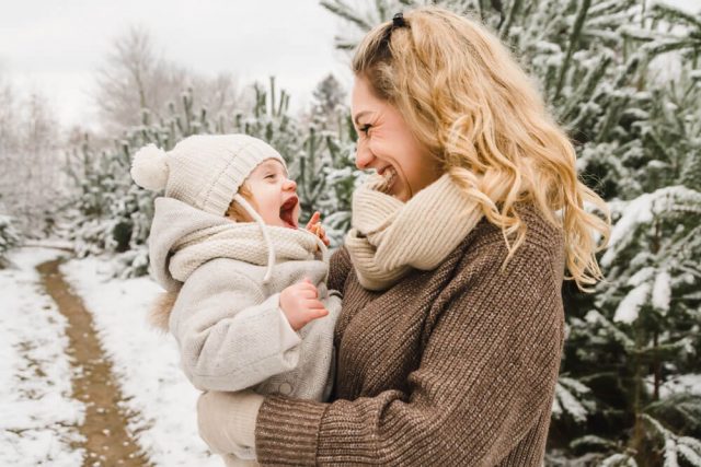 Mama und Tochter lachen herzhaft bei Familienfotos im Schnee in Rostock