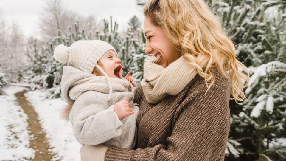 Mama und Tochter lachen herzhaft bei Familienfotos im Schnee in Rostock