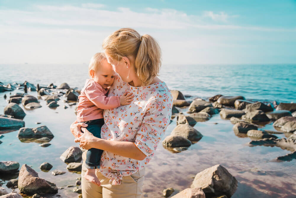 Kleinkind kuschelt ihre Mama am Strand von Heiligendamm im Sommer