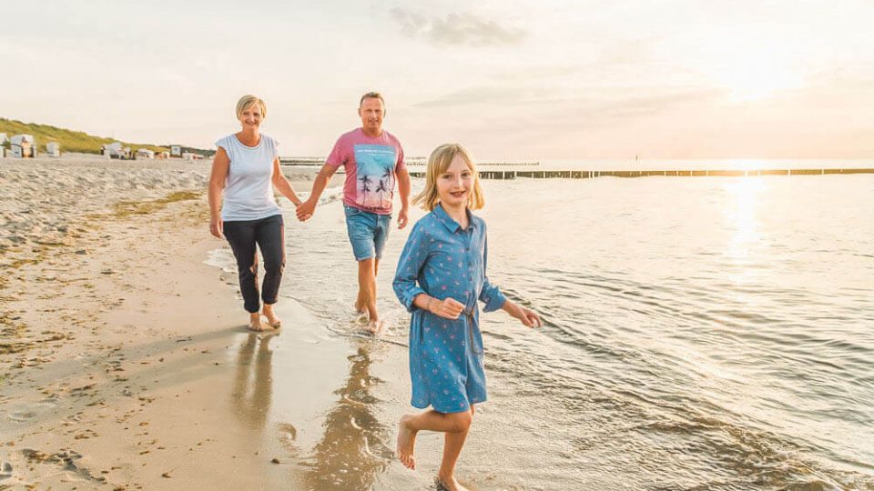 Fotoshooting mit Fotografin aus Rostock am Strand von Graal-Müritz. Die Familie rennt durch die Ostsee.