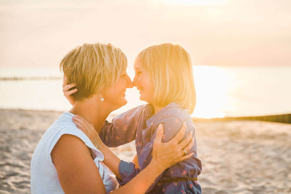 Mama und Tochter geben sich einen Nasenkuss beim Familien-Fotoshooting in Graal-Müritz am Strand zum Sonnenuntergang