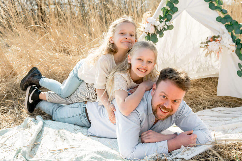 Die Kinder liegen auf Papa's Rücken beim Fotoshooting - Familienfotos & Babybauchfotos in Rostock