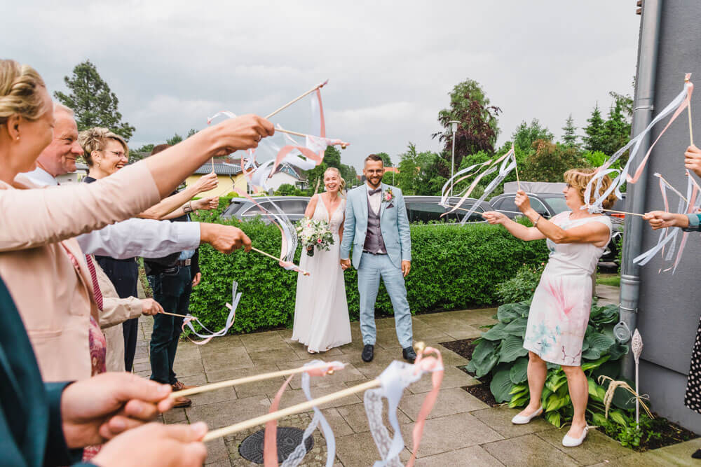 Hochzeitsgäste wedeln mit den Wedding Wands zur Begrüßung des Brautpaares trotz Regen - Hochzeitsfeier in Zingst an der Ostsee