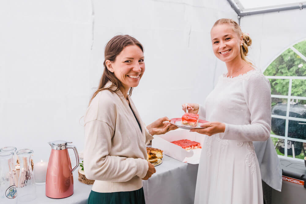 Die Braut und die Hochzeitsfotografin stehen beim Kuchen - Hochzeitsfeier in Zingst an der Ostsee