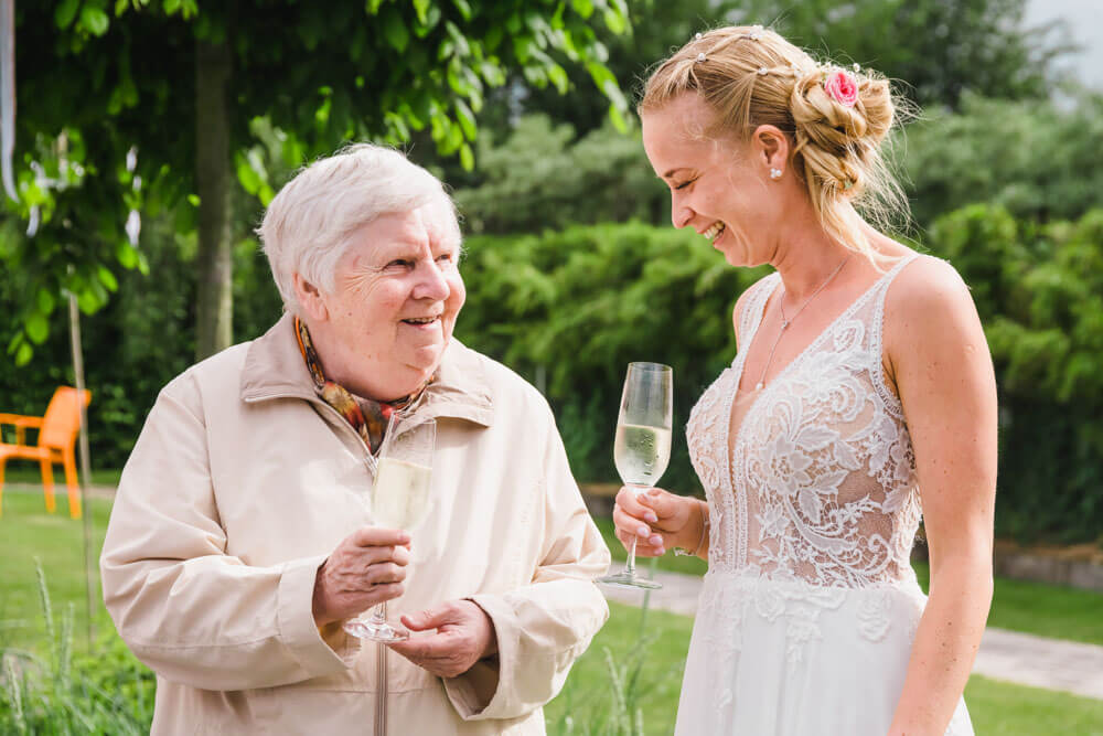 Die Braut unterhält sich im Garten mit ihrer Oma. Hochzeitsreportage. Hochzeitsfeier in Zingst an der Ostsee