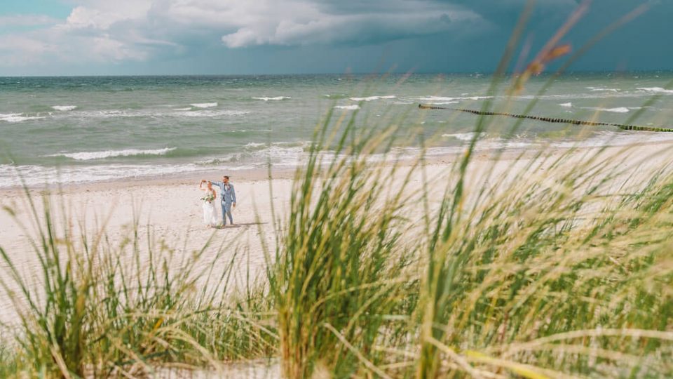 Das Hochzeitspaar tanzt am Strand. Brautpaarfotos am Ostseestrand auf dem Darss in Mecklenburg-Vorpommern. Hochzeitsfotograf an der Ostsee (Markgrafenheide, Graal-Müritz, Dierhagen, Ahrenshoop, Wustrow, Prerow, Zingst).