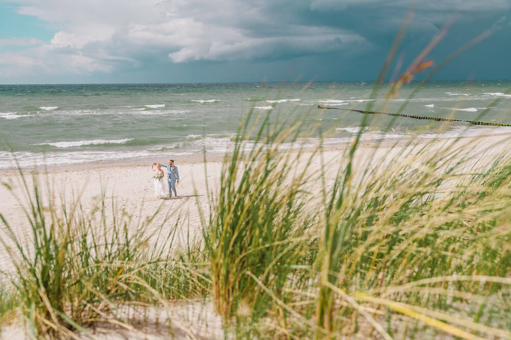 Das Hochzeitspaar tanzt am Strand. Brautpaarfotos am Ostseestrand auf dem Darss in Mecklenburg-Vorpommern. Hochzeitsfotograf an der Ostsee (Markgrafenheide, Graal-Müritz, Dierhagen, Ahrenshoop, Wustrow, Prerow, Zingst).