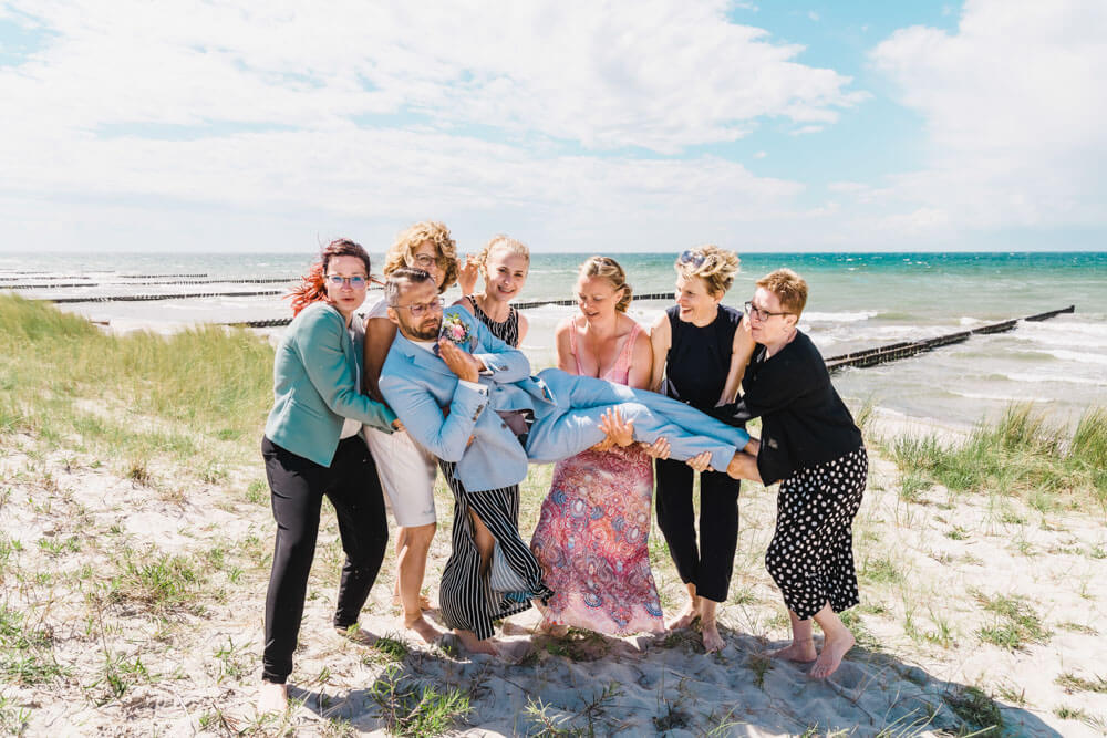 Witziges Gruppenfoto zur Hochzeit am Strand von Ahrenshoop in den Dünen. Hochzeitsfotograf an der Ostsee (Markgrafenheide, Graal-Müritz, Dierhagen, Ahrenshoop, Wustrow, Prerow, Zingst).