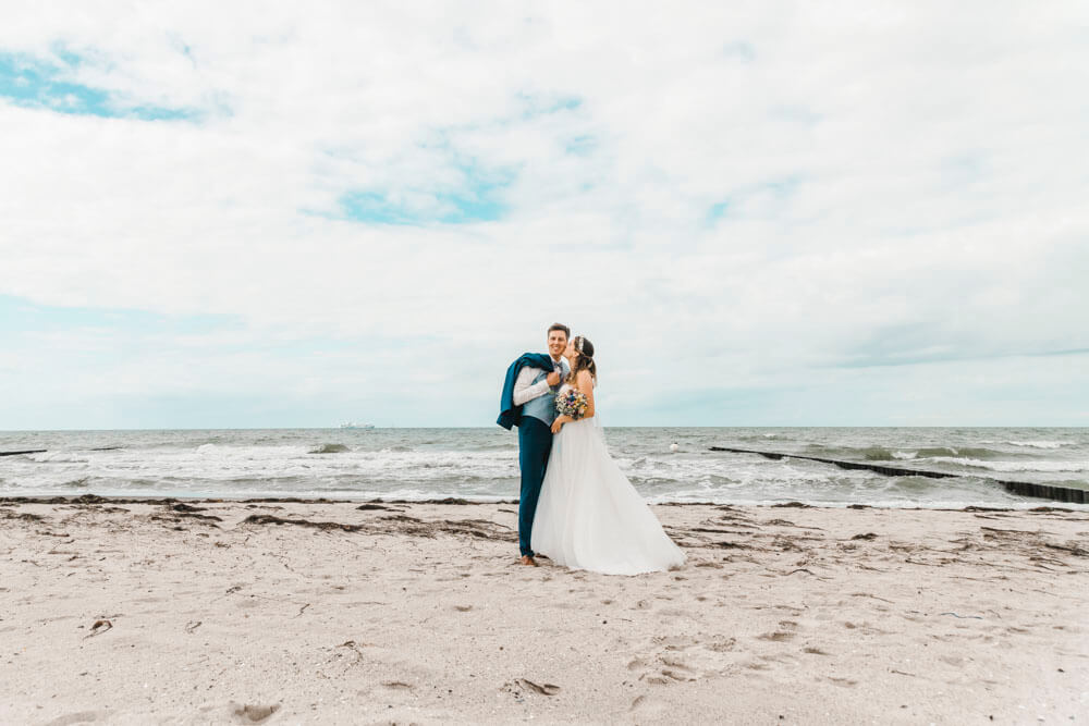 Braut und Bräutigam stehen am Strand von Markgrafenheide während ihrem Fotoshooting.