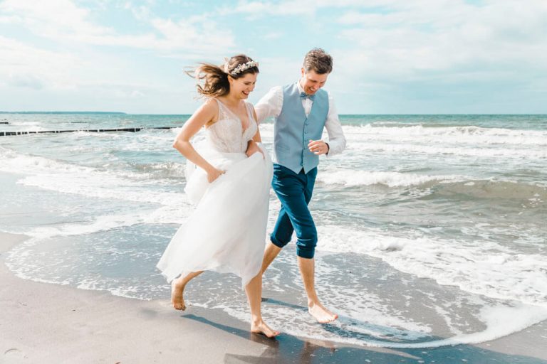 Hochzeitsfoto: Brautpaar rennt am am Strand entlang.