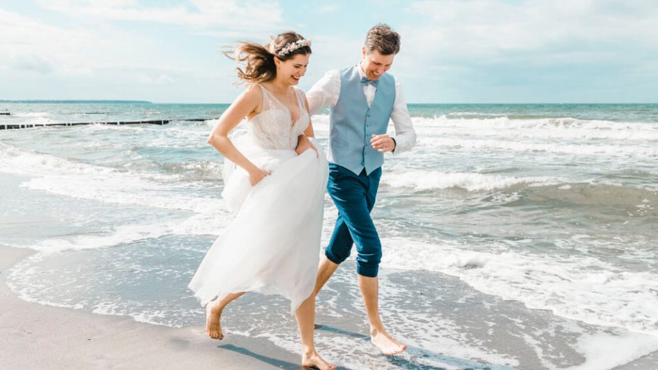 Hochzeitsfoto: Brautpaar rennt am am Strand entlang.