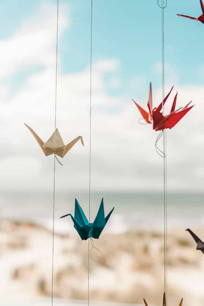 Hochzeitsdeko: Selbst gebastelte Origami-Kraniche hängen am Fenster mit Blick auf die Ostsee.
